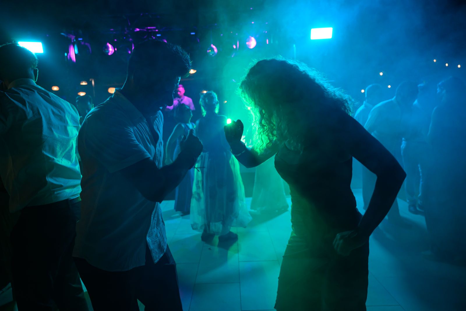 Invitados bailan a contraluz entre humo y luces de colores en la pista